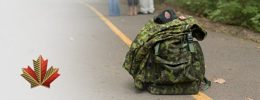 A bag with the cadpat print and a beret on top of the bag laying in the middle of the road.