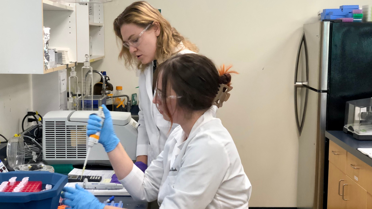 Two lab technicians work at a counter with science equipment at University of Victoria’s Proteomics Centre